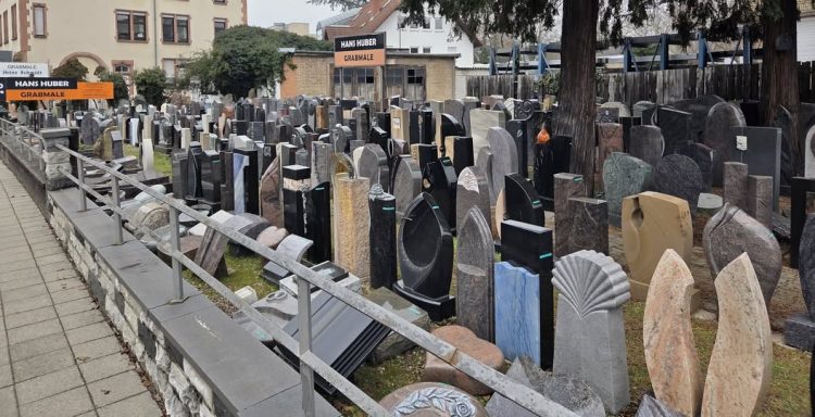 Ein Friedhof mit zahlreichen Grabsteinen und Grabanlagen in einer städtischen Umgebung.