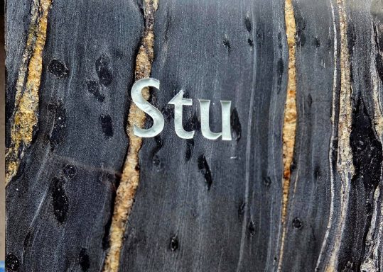 Graue Steinoberfläche mit dem eingeprägten Text "Stu".