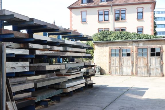 Holzregale mit Brettern vor einem Gebäude mit Fenster und einer alten Tür.
