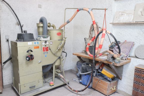 Werkstatt mit einer Maschine zur Verarbeitung von Materialien und einem Arbeitstisch.