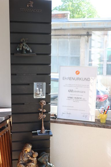 Eine Wand mit Holzregal, mehreren Statuen und einem Informationsblatt.