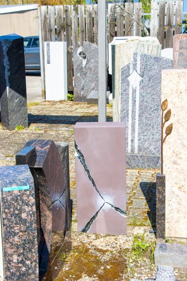 Verschiedene Grabsteine aus verschiedenen Materialien und Farben auf einem Friedhof.
