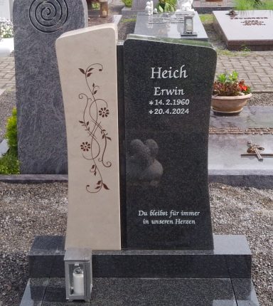 Grabstein mit gravierten Ornamenten, Namen und Daten auf schwarzem und hellem Stein.