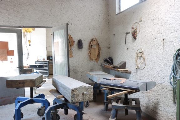 Werkstatt mit Holzmaterialien, Werkzeug und hellen Wänden.