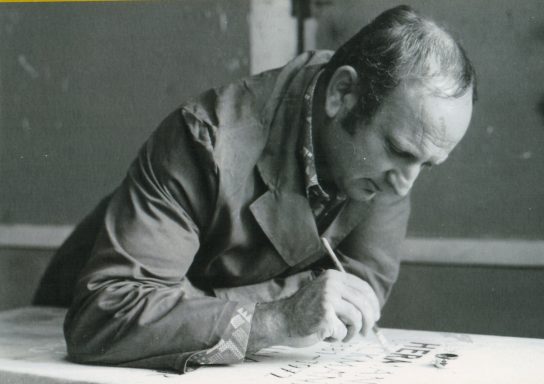 Ein Mann arbeitet konzentriert mit einem Stift auf einem Blatt Papier.